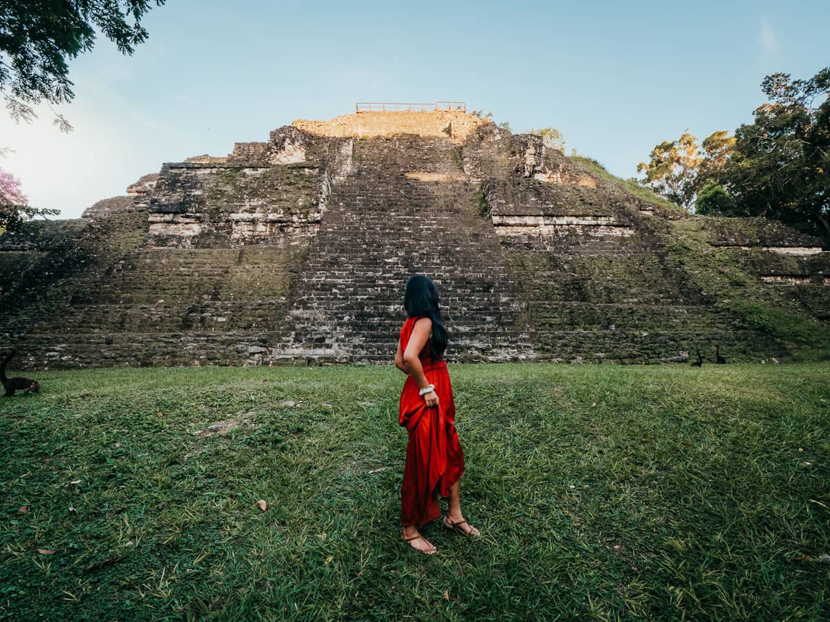 Back of woman wearing red dress looking at temple in Tikal, best things to do in Flores Guatemala Itinerary