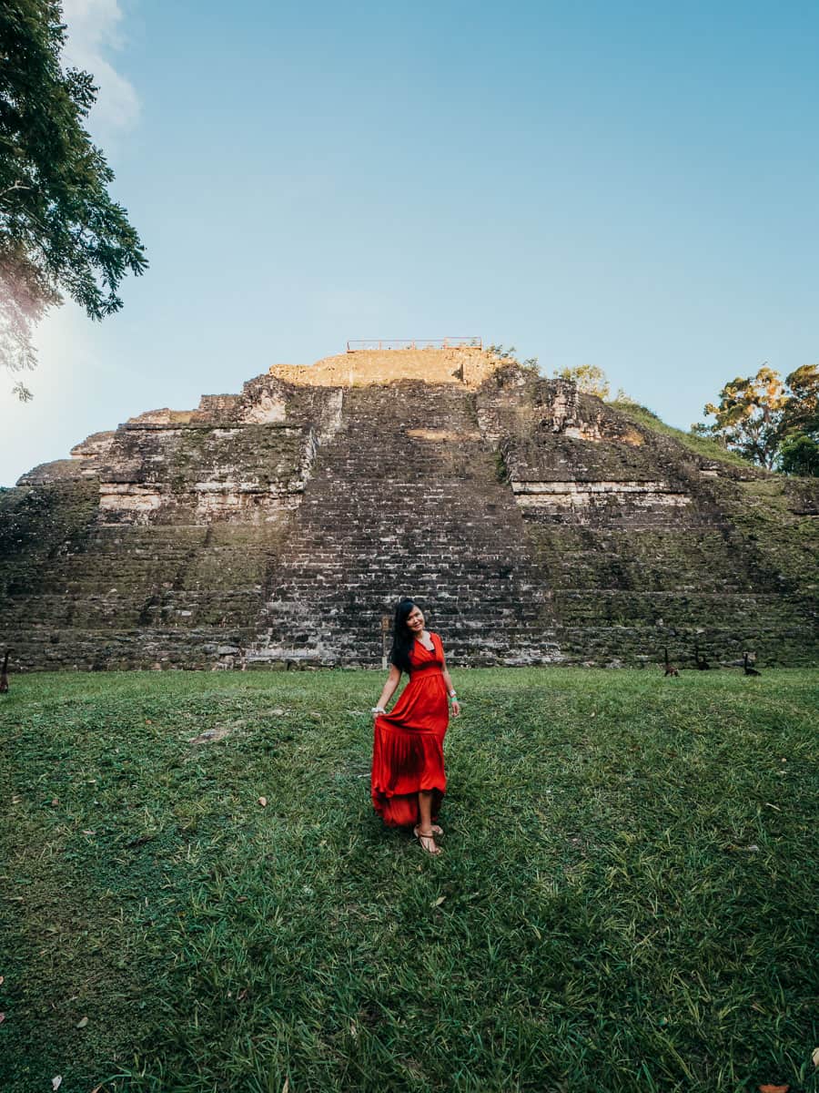 Woman wearing red dress in front of temple in Tikal