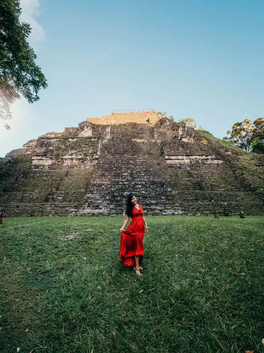 Woman wearing red dress in front of temple in Tikal