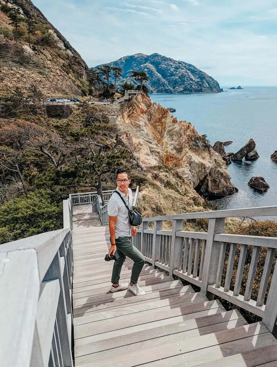 man standing on wooden staircase with camera in izu peninsula