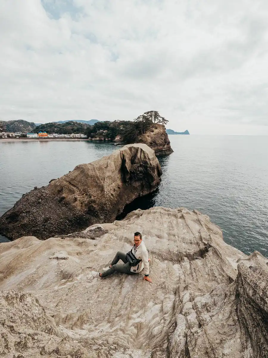 man sitting on the rocky outcrop of izu peninsula