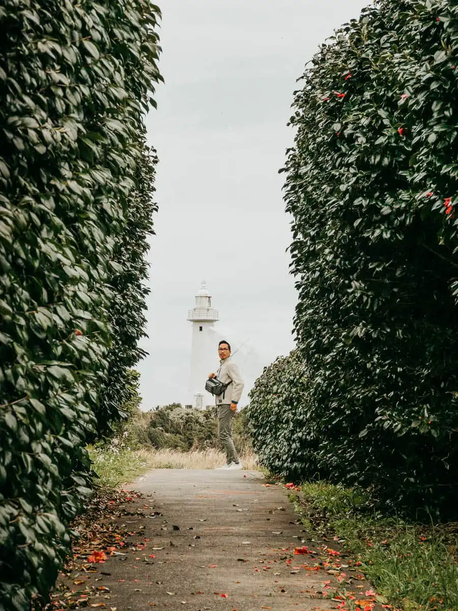 man standing in front of white light house with umbrella