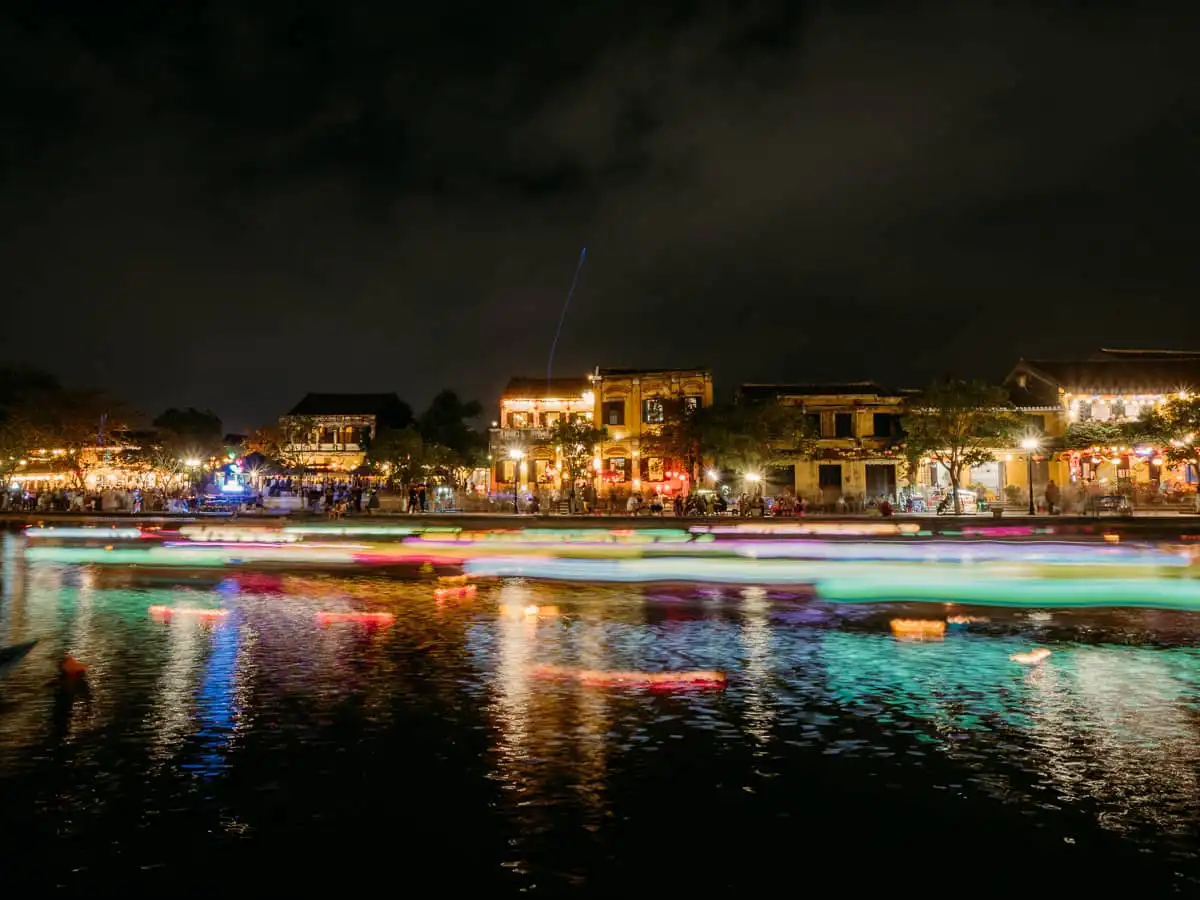 lanterns and boats going by at night in Hoi An