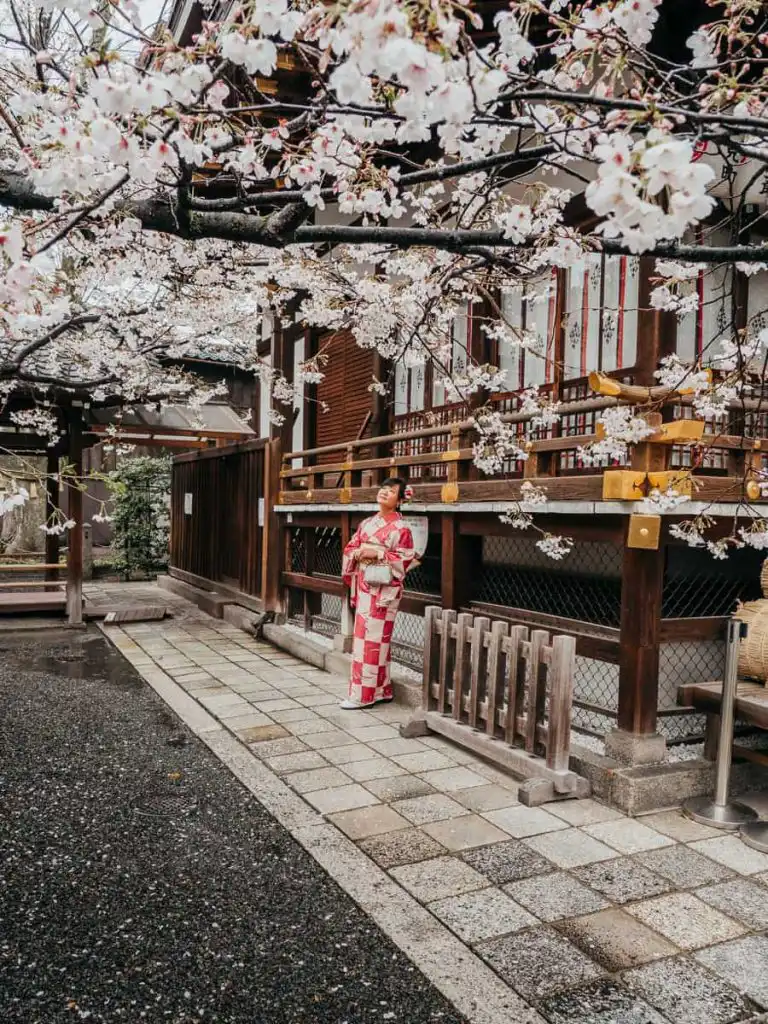 woman dressed in kimono in front of ancient building in kyoto