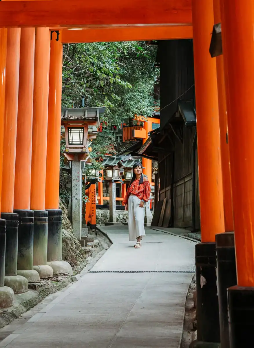 woman standing in rows of torii gates at Fushimi Inarii