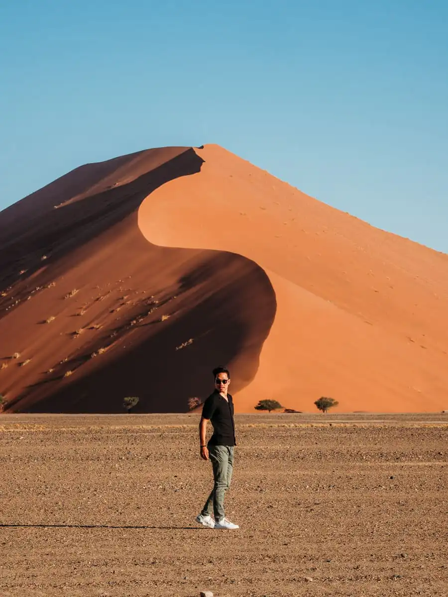 man standing in front of the red dunes in Sossusvlei