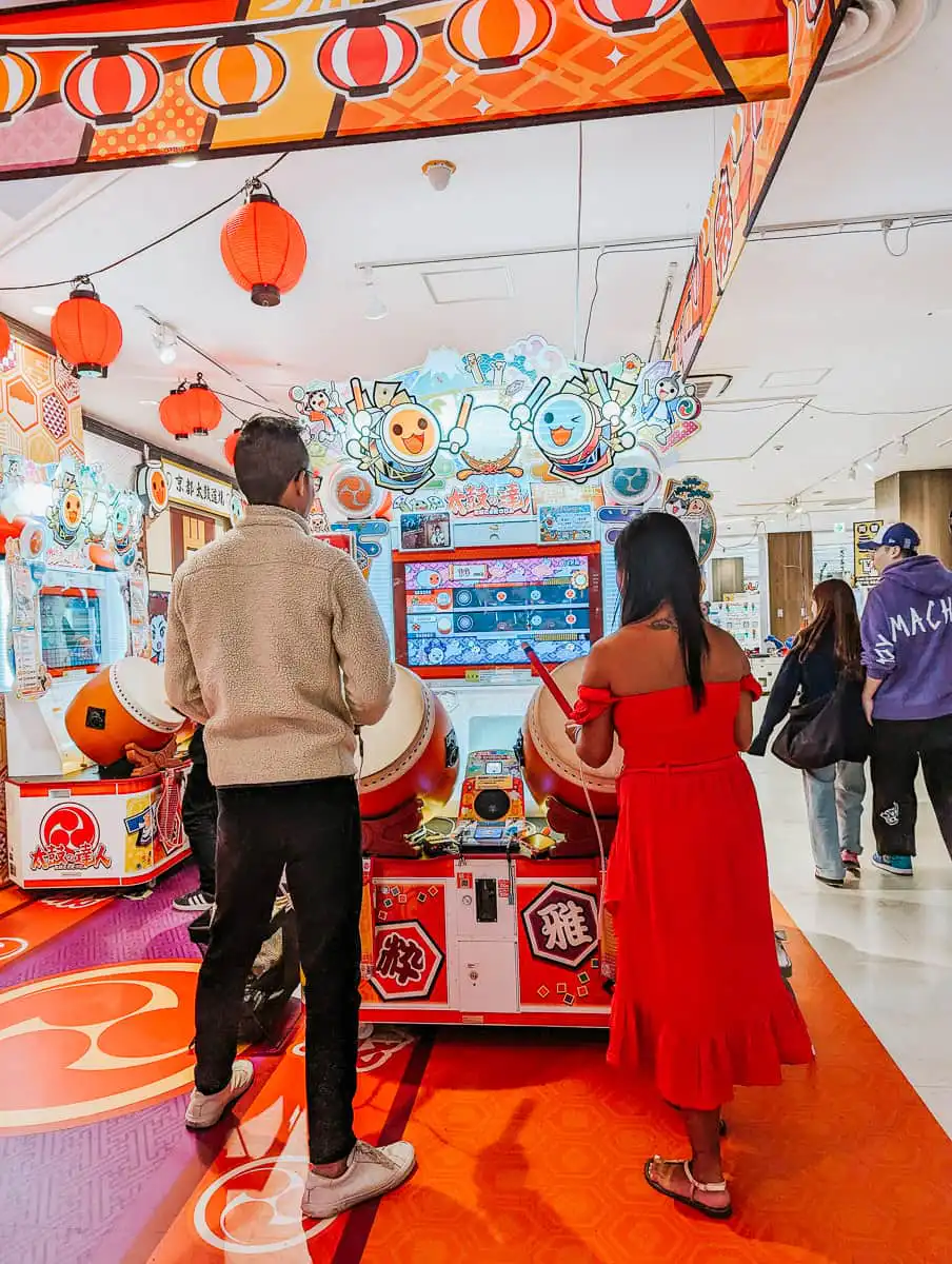 man and woman playing taiko arcade drumming game