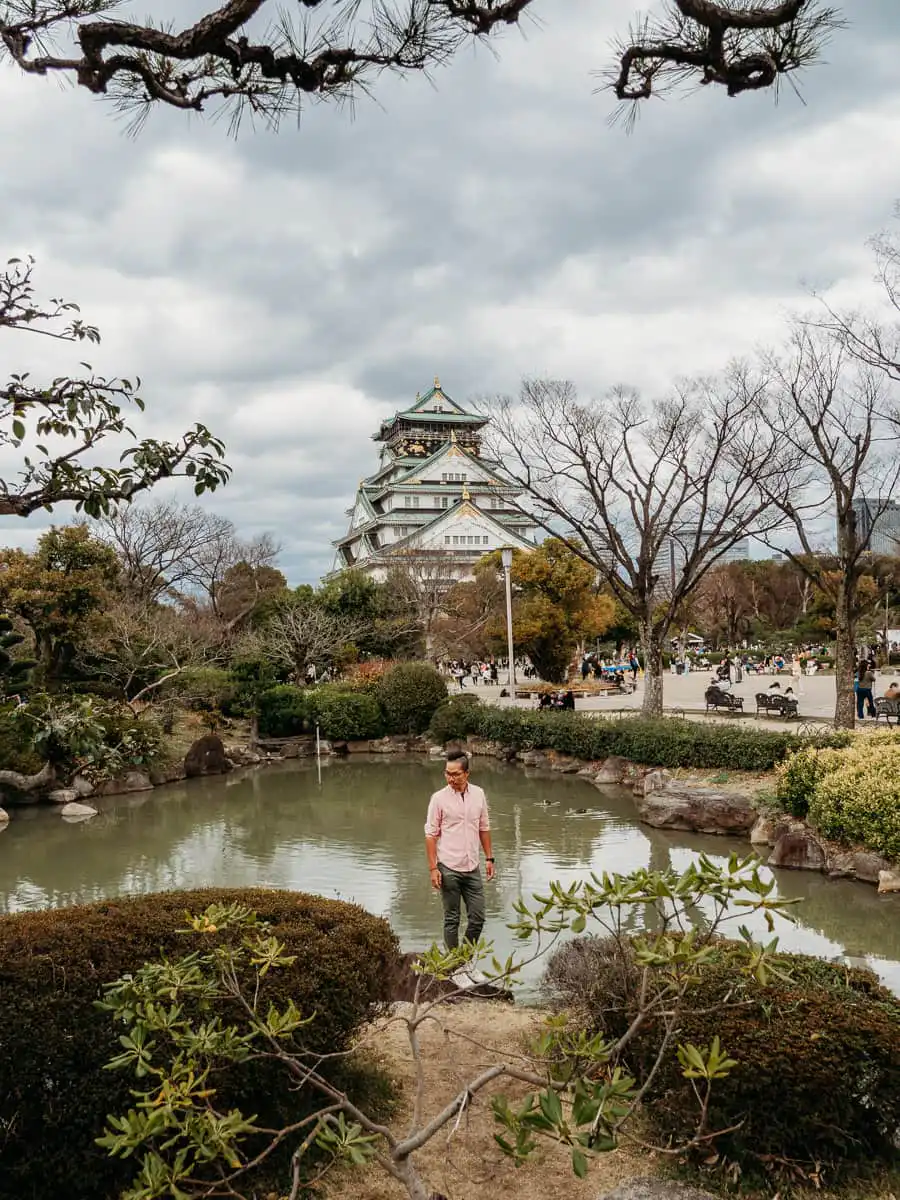 man standing in front of lake in front of osaka castle, an amazing activity during one day in osaka