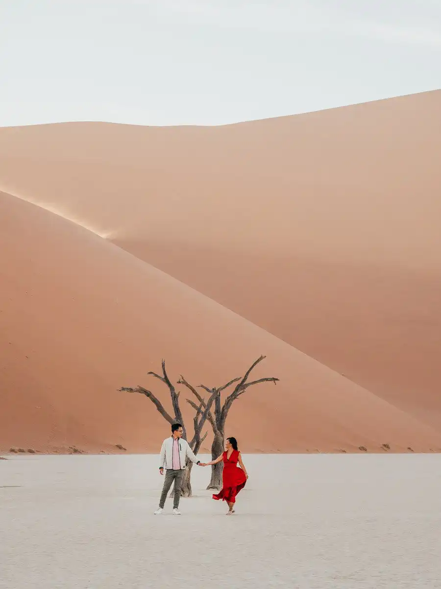 Man and woman standing in front of tree in Deadvlei