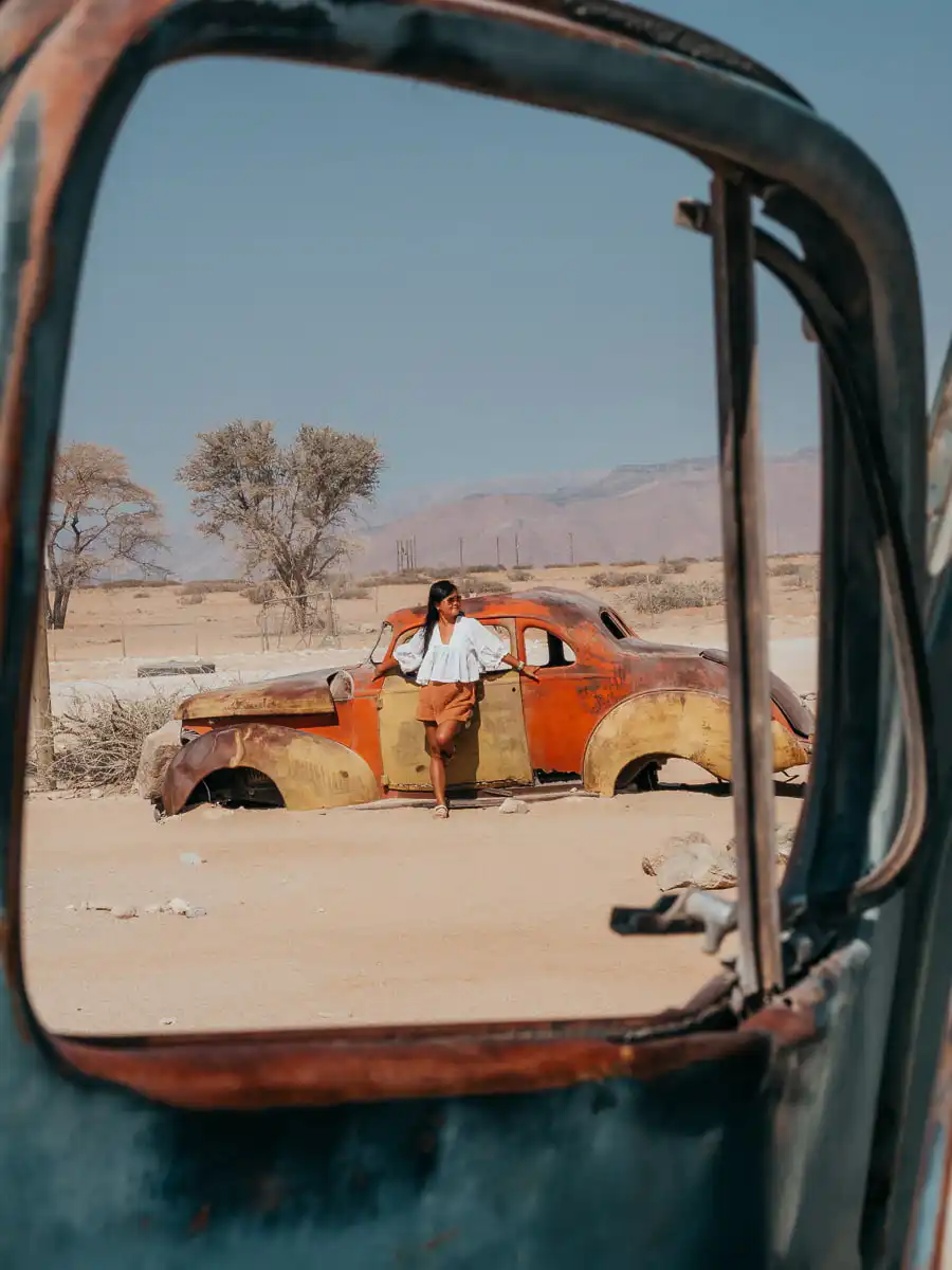 Woman posing next to a vintage car in Namibia Solitaire
