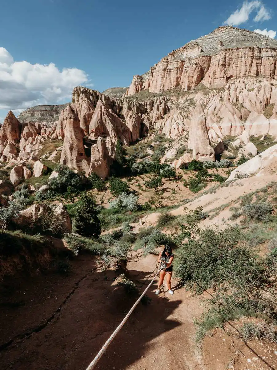 holding onto rope to descend a steep slope in Cappadocia