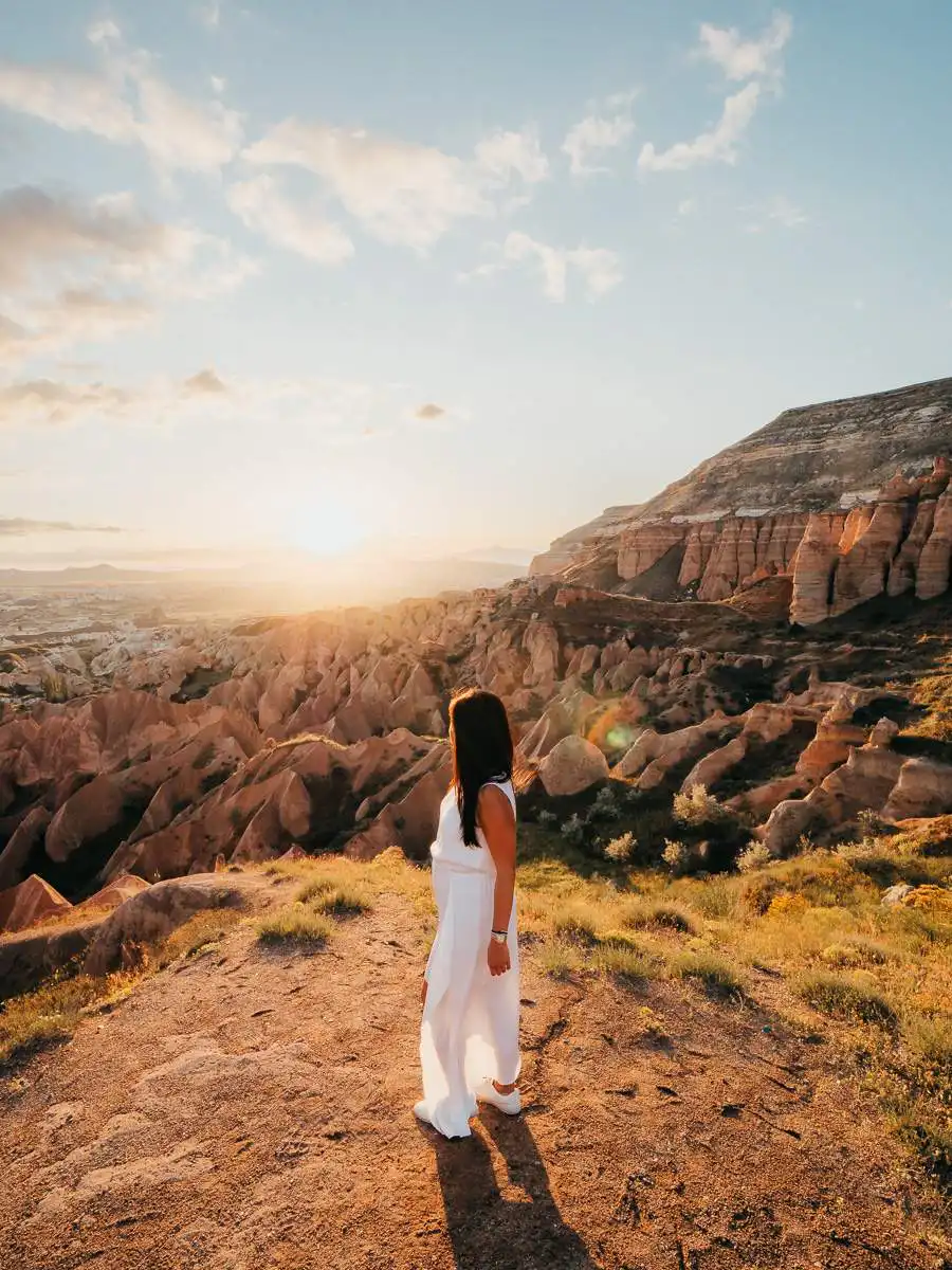 woman standing near cliff in Cappadocia during sunset