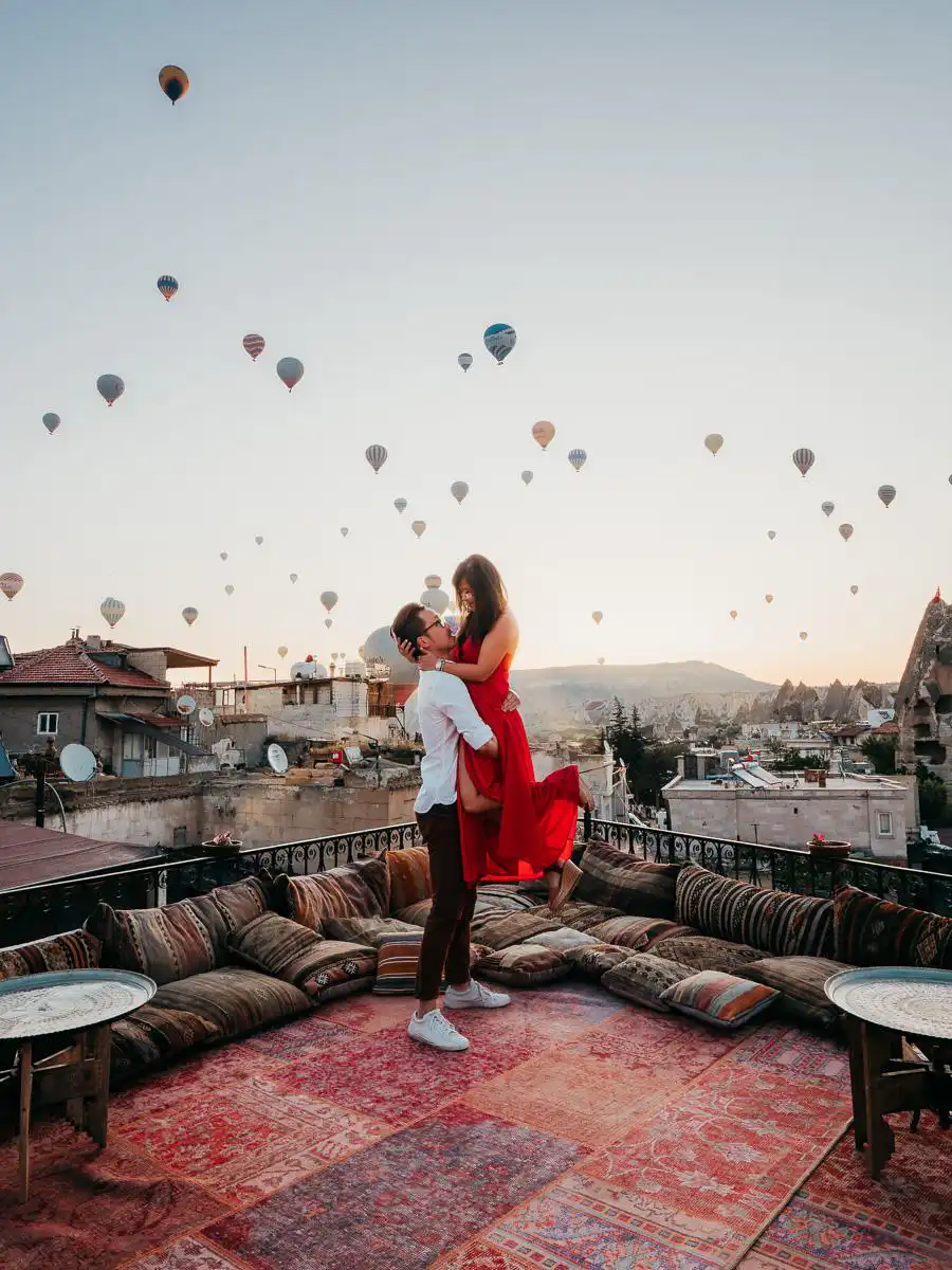 Man and woman standing on a turkish carpet in front of the hot air balloon of Cappadocia