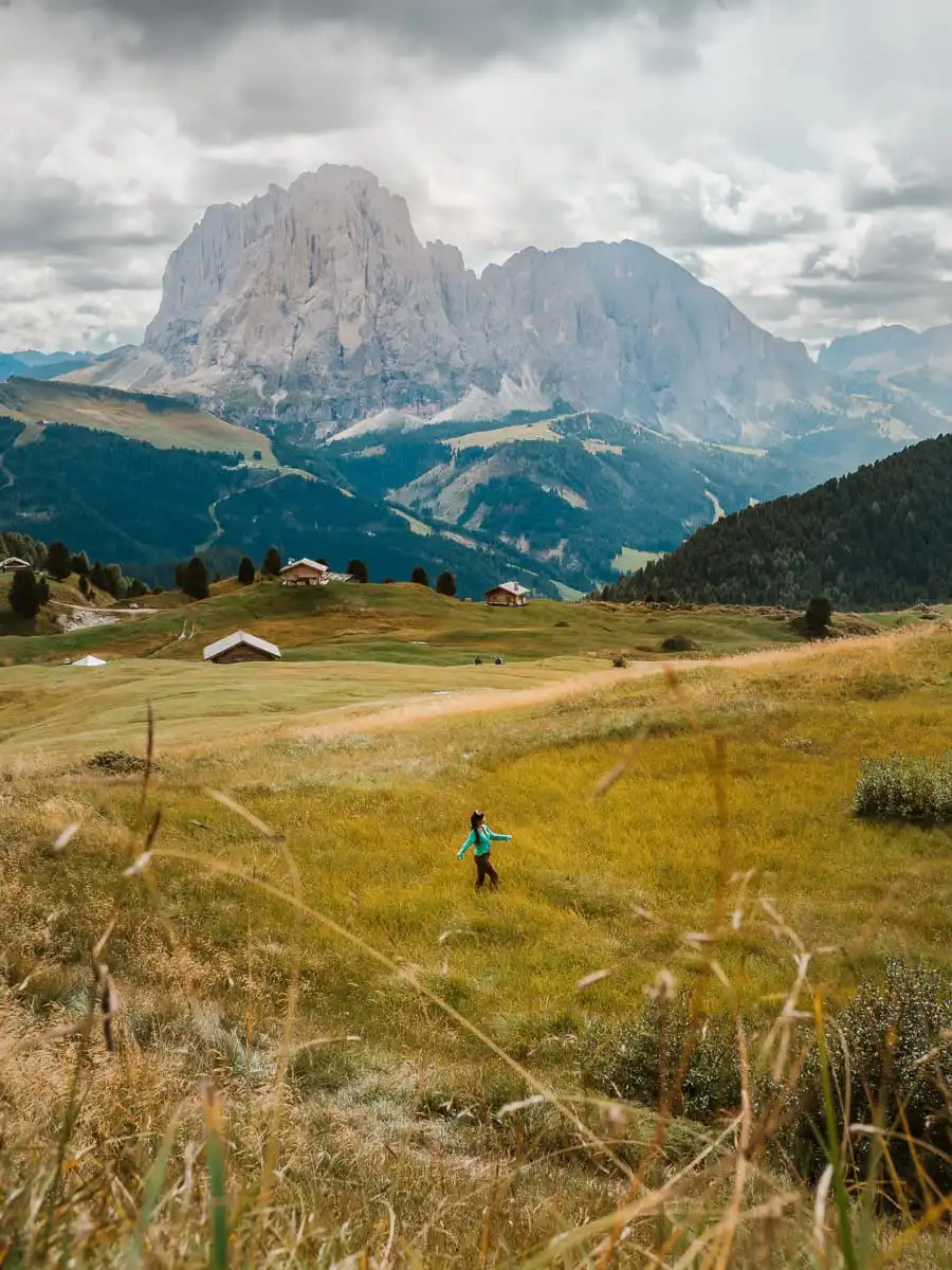 Valley in Seceda with green grass and woman standing in the field