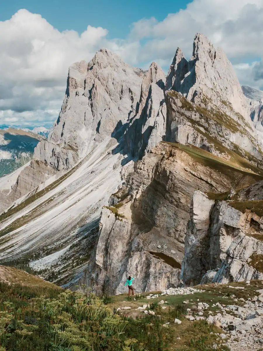 Seceda mountain ridge with woman standing near the grass