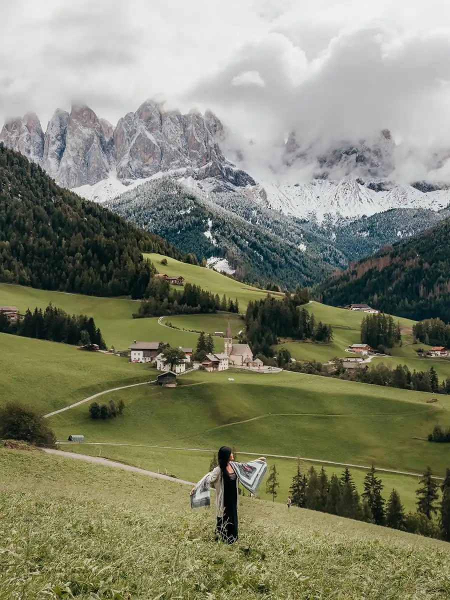 Woman standing in front of church in Val di Funes in the dolomites