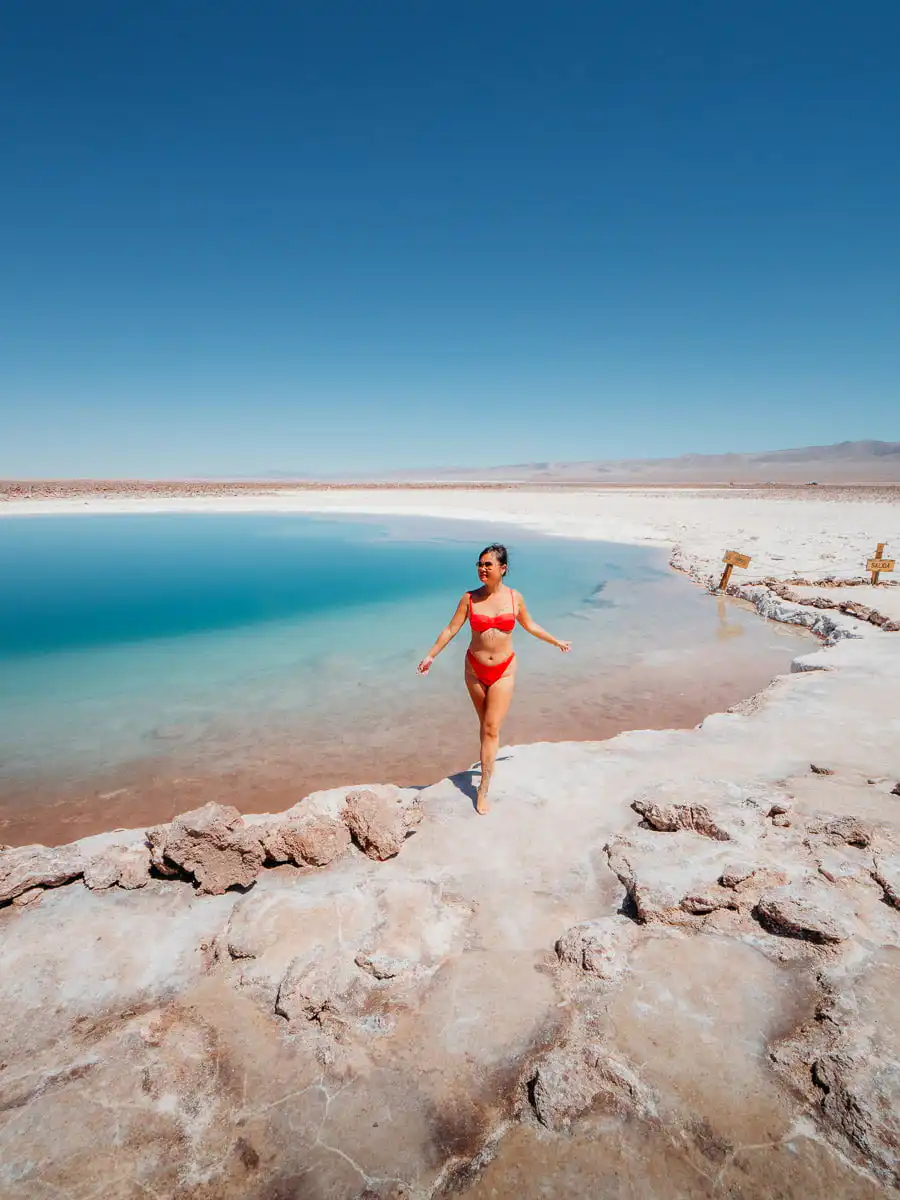 Woman in bikini standing in front turquoise salt pool