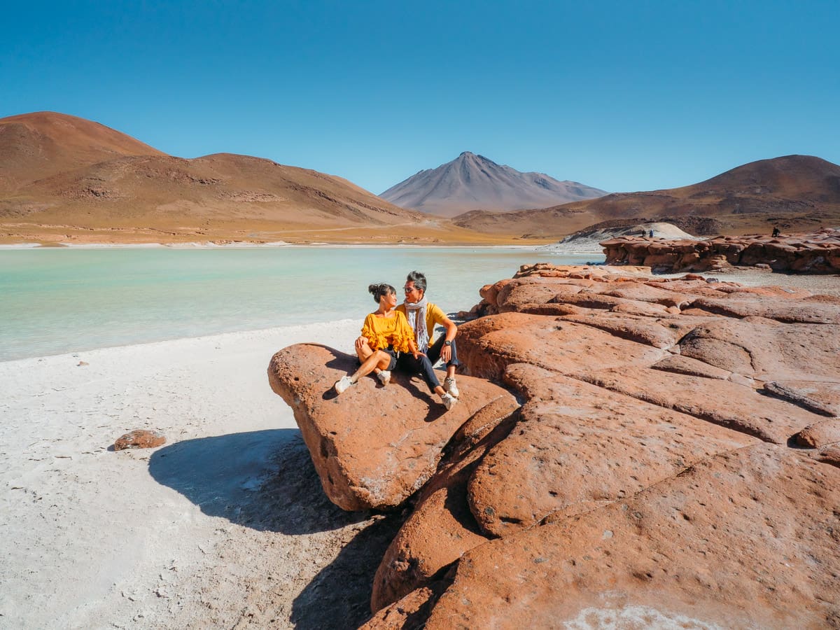 couple sitting together on the red rock of Piedras Rojas beside laguna