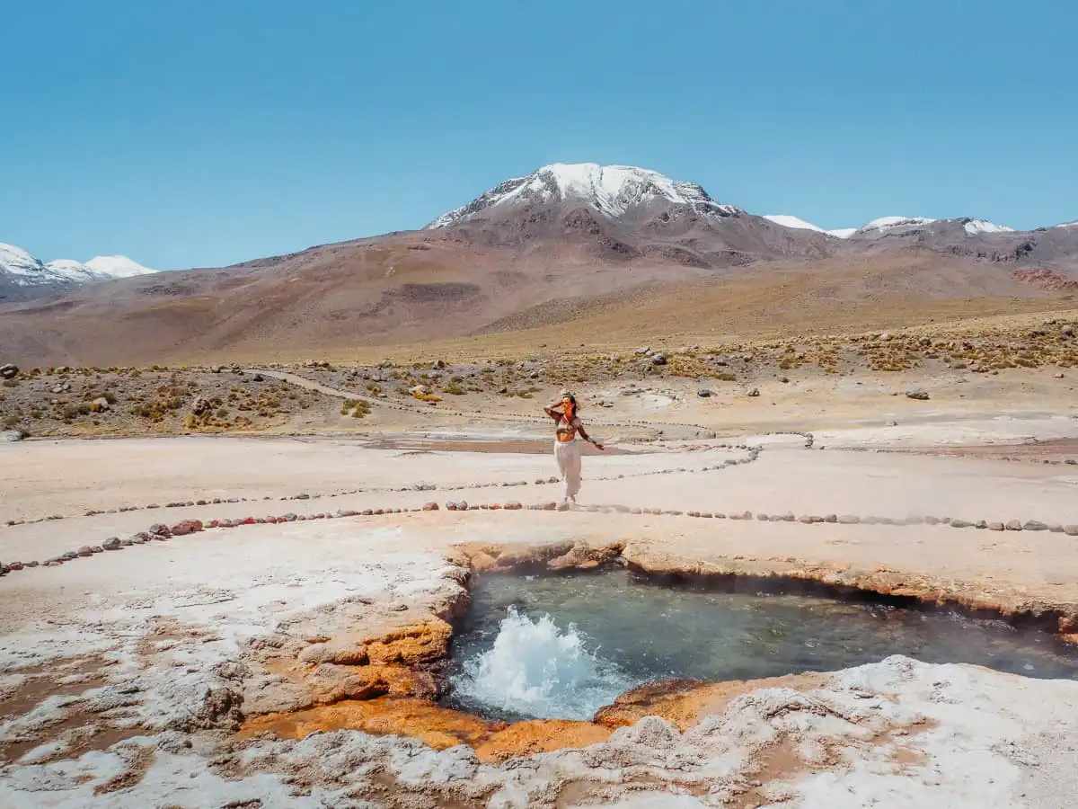 woman standing in front of geyser in el tatio