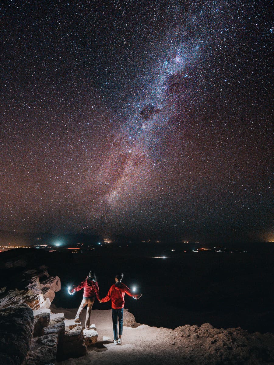 Couple standing in the dark doing star photography in the Atacama desert