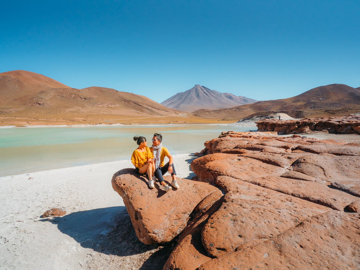 Couple sitting on the red rocks at Piedras Rojas in Atacama Desert Chile
