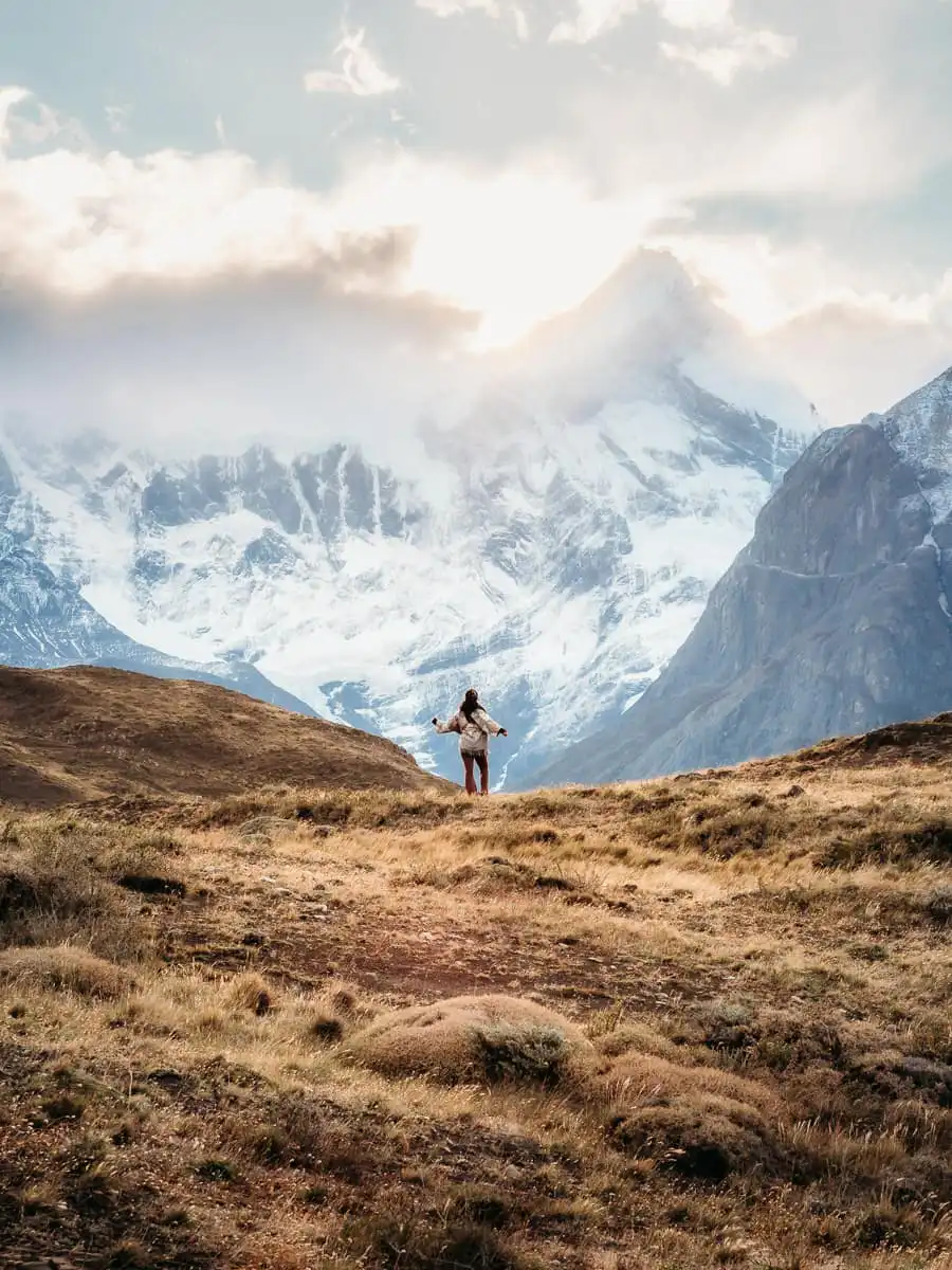 Watching the mountains in Torres del Paine, woman standing far on the ridge