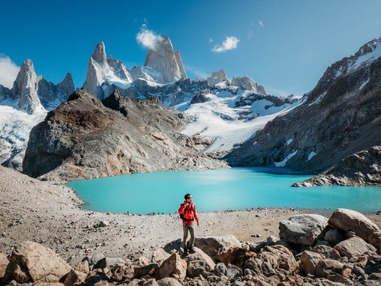 man standing at the top of Laguna los Tres hike with blue lagoon