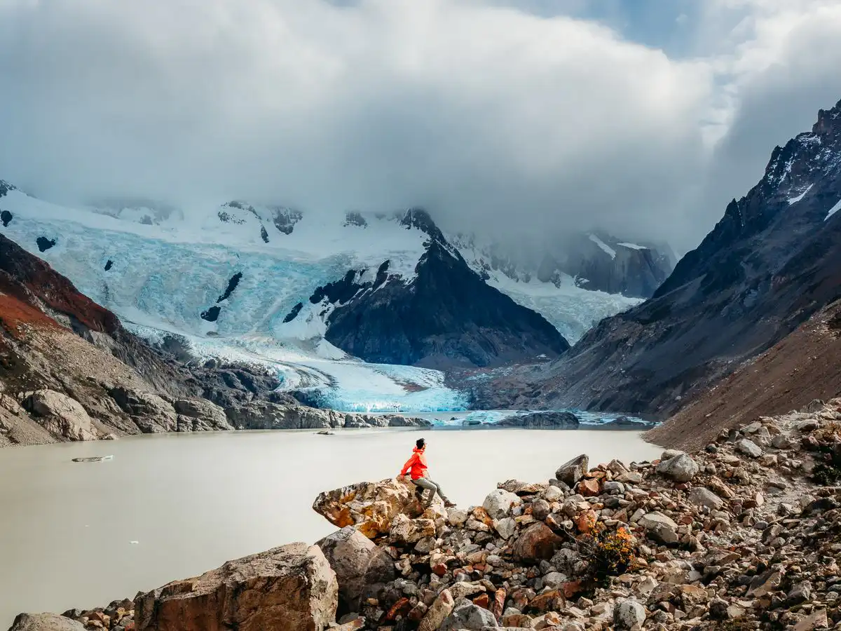 man sitting on rock in front of glacier in Patagonia