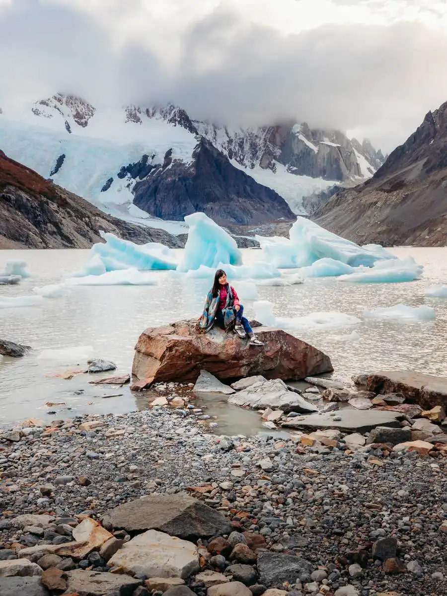 woman sitting on rock in front of icebergs, one of the best places we stay during our 1 week in Argentina Patagonia