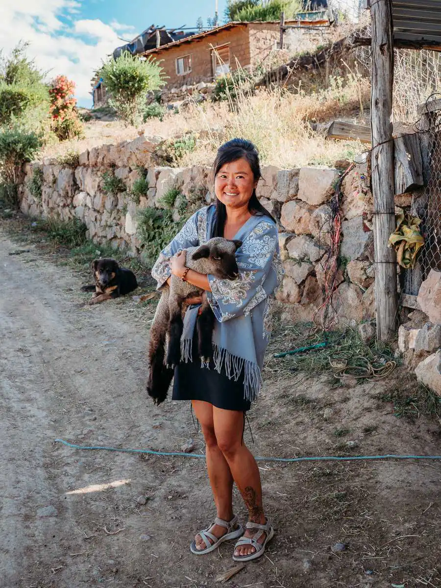 holding a goat at la granja del colca