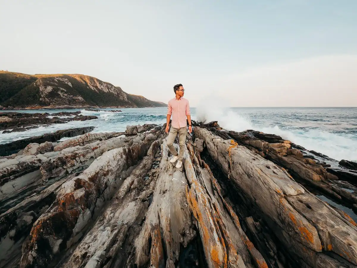 man standing on coastal rocks at storms river mouth