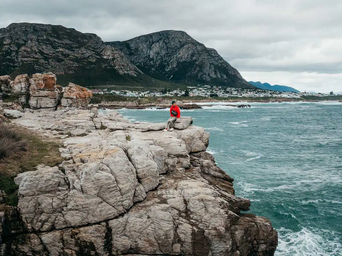 sitting on a rock at hermanus cliff coastal walk