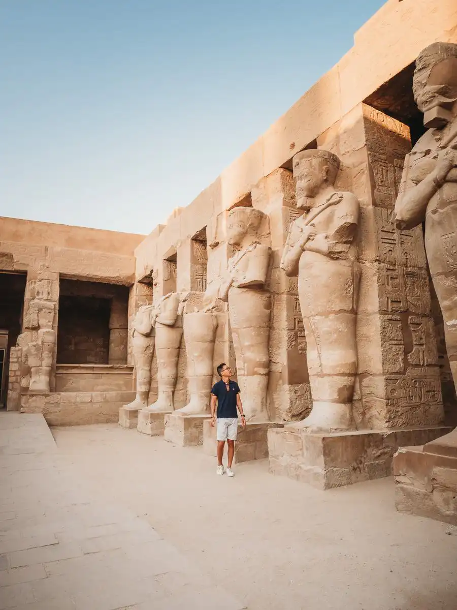 Man standing next to statues in Valley of the Kings