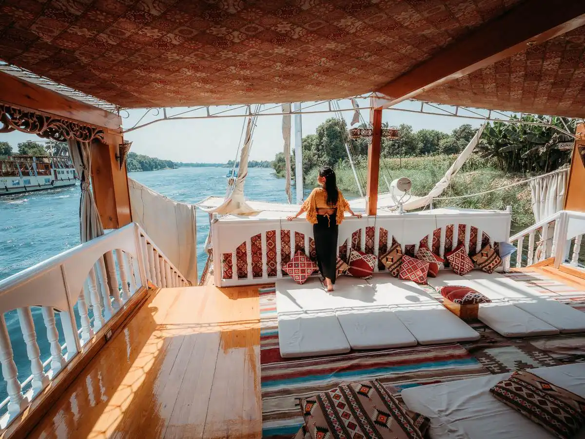 standing on the cushions on the back of the Dahabiya boat watching the view