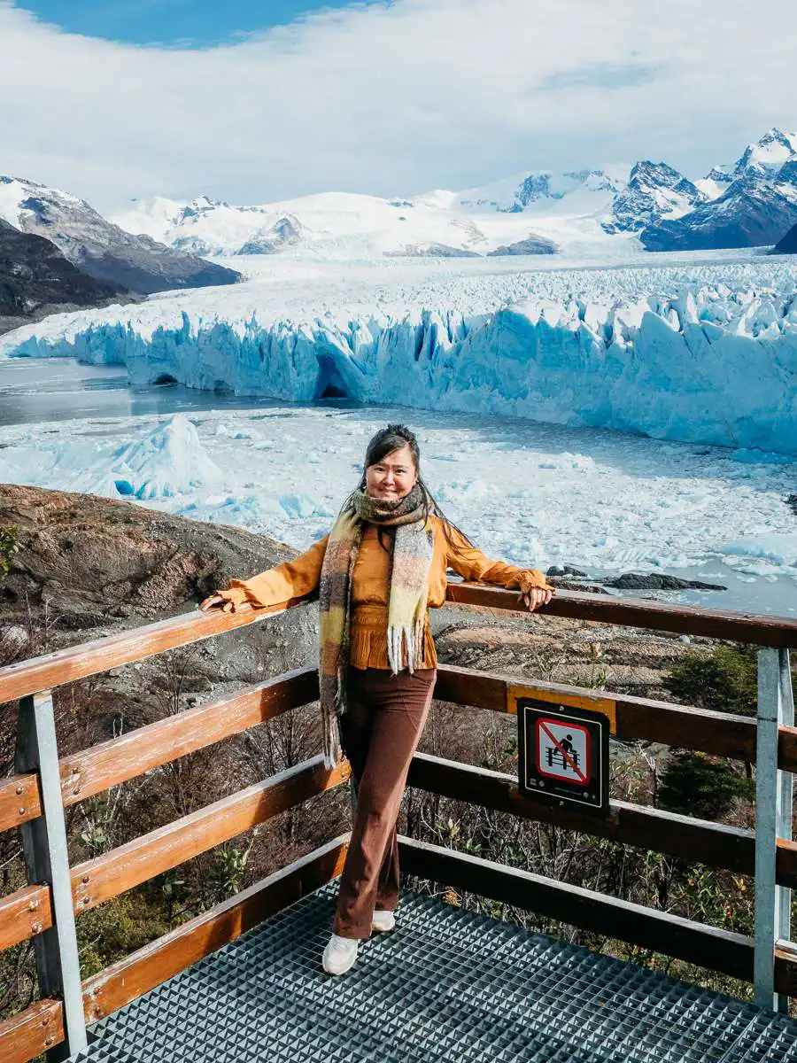 woman standing at corner of boardwalk with view of perito moreno glacier