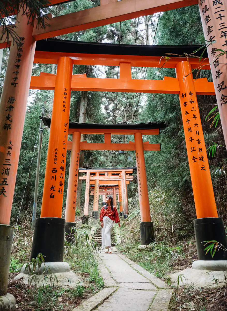 forest part of fushimi inari, woman standing among the red tori gates