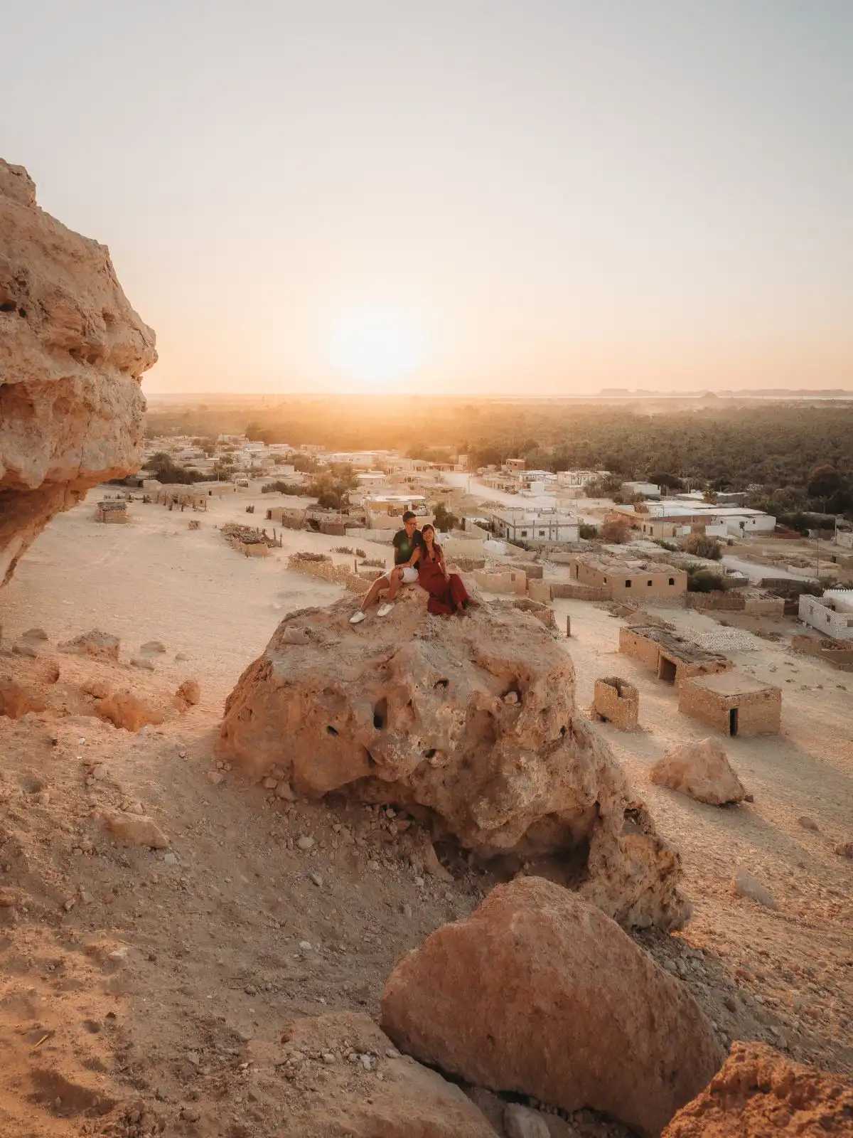 both sitting on a stone in siwa oasis at sunset