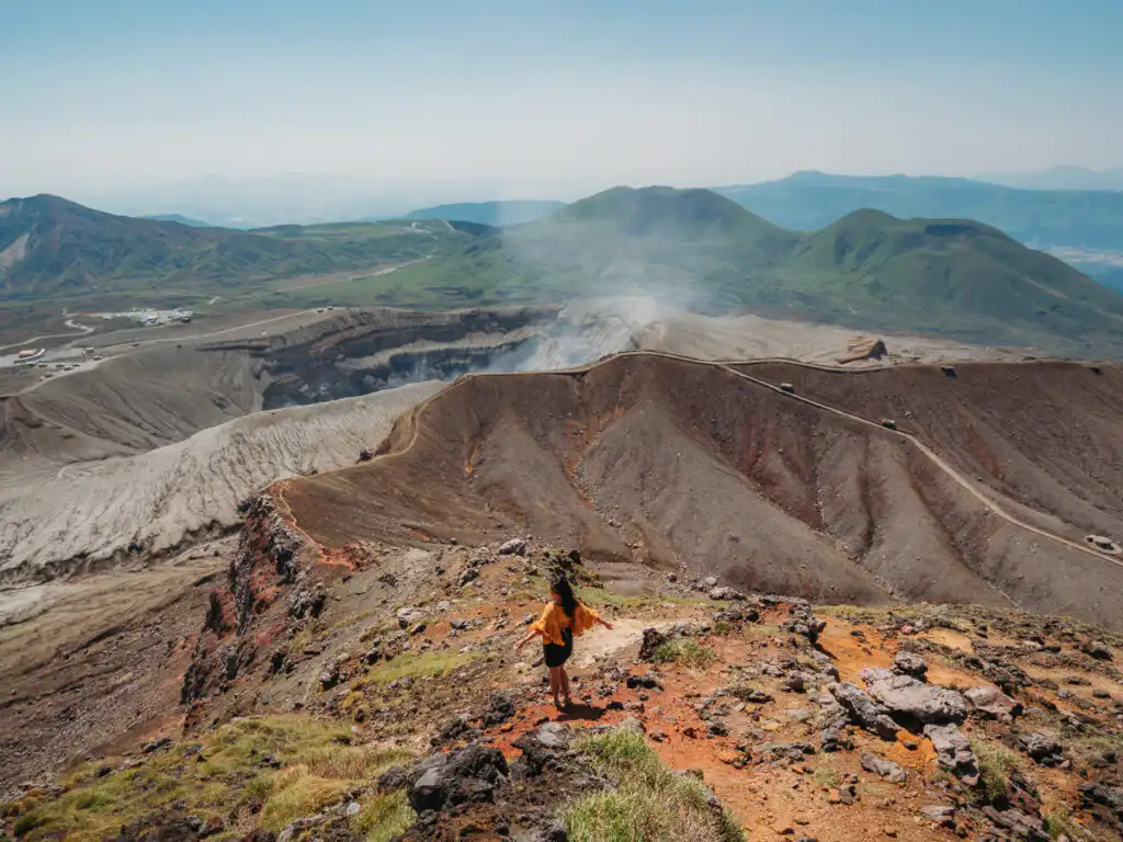 woman standing in front of mount aso crater