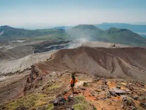 woman standing in front of mount aso crater