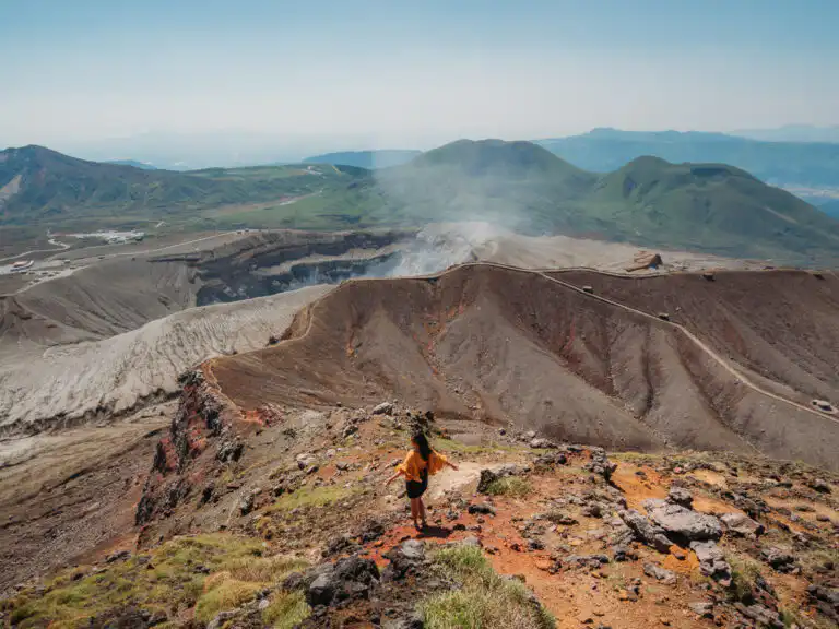 woman standing in front of mount aso crater