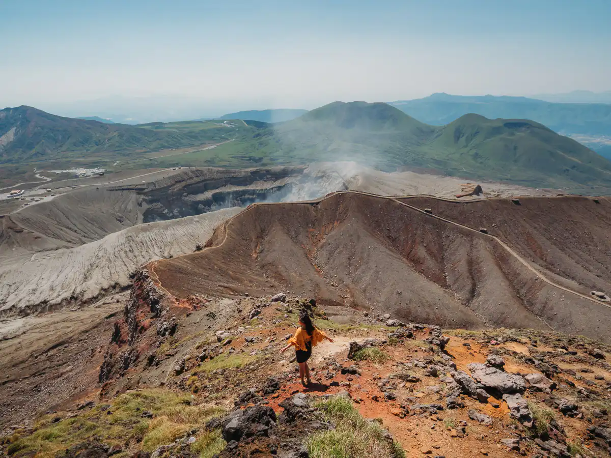 woman standing in front of mount aso crater