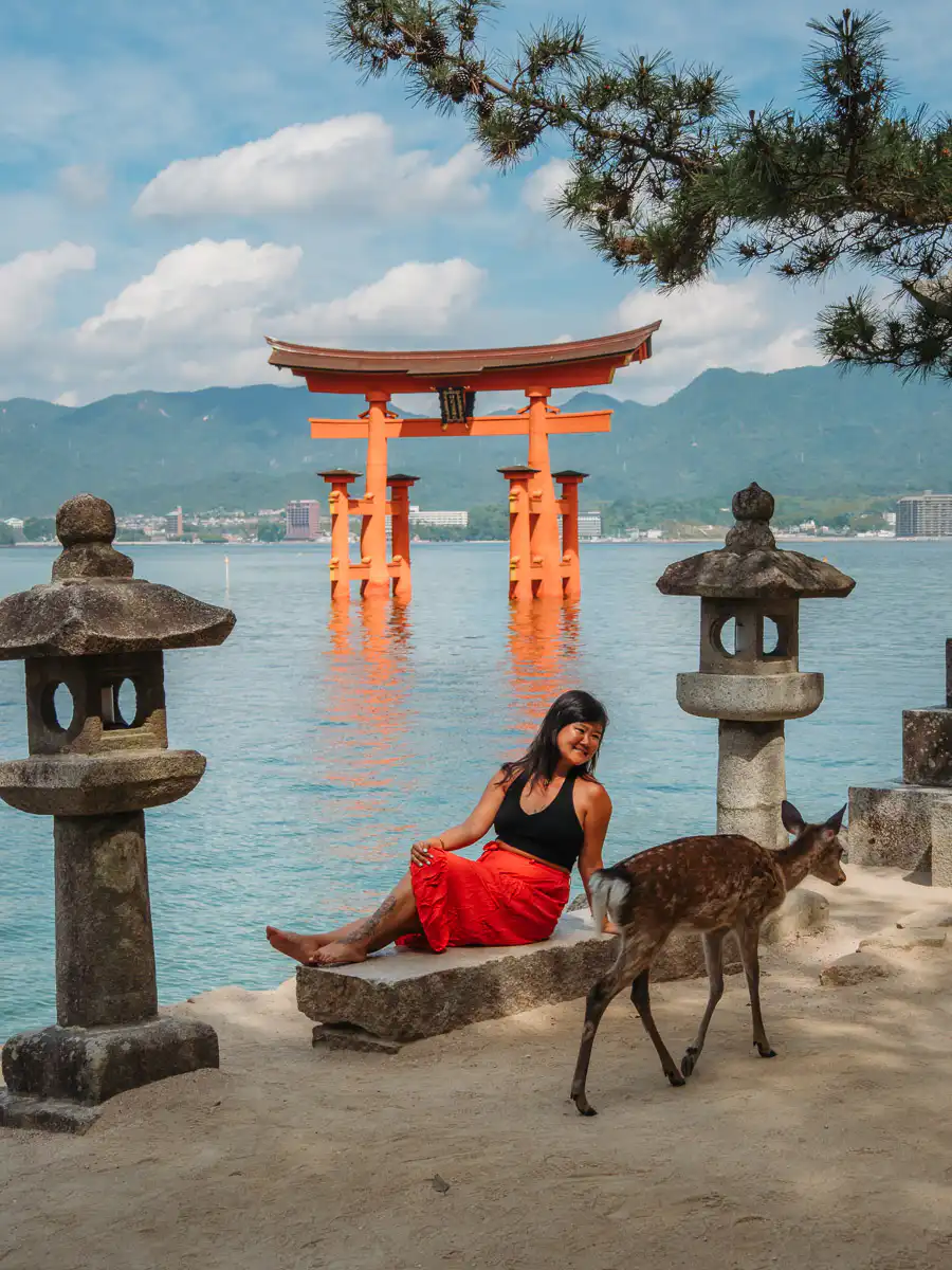 deer walking past woman in miyajima