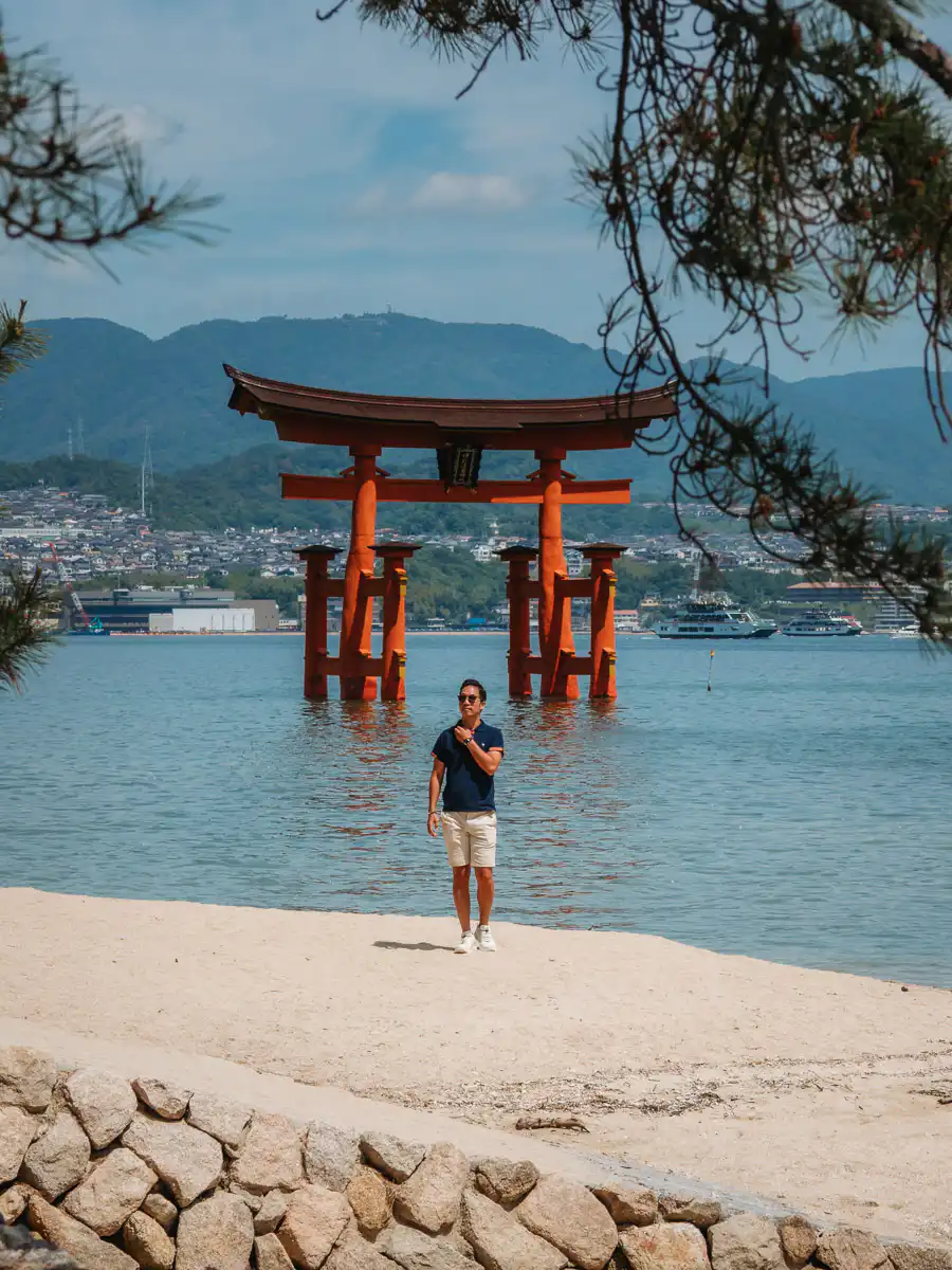 Man standing on the beach at Miyajima in front of the tori gates at high tide