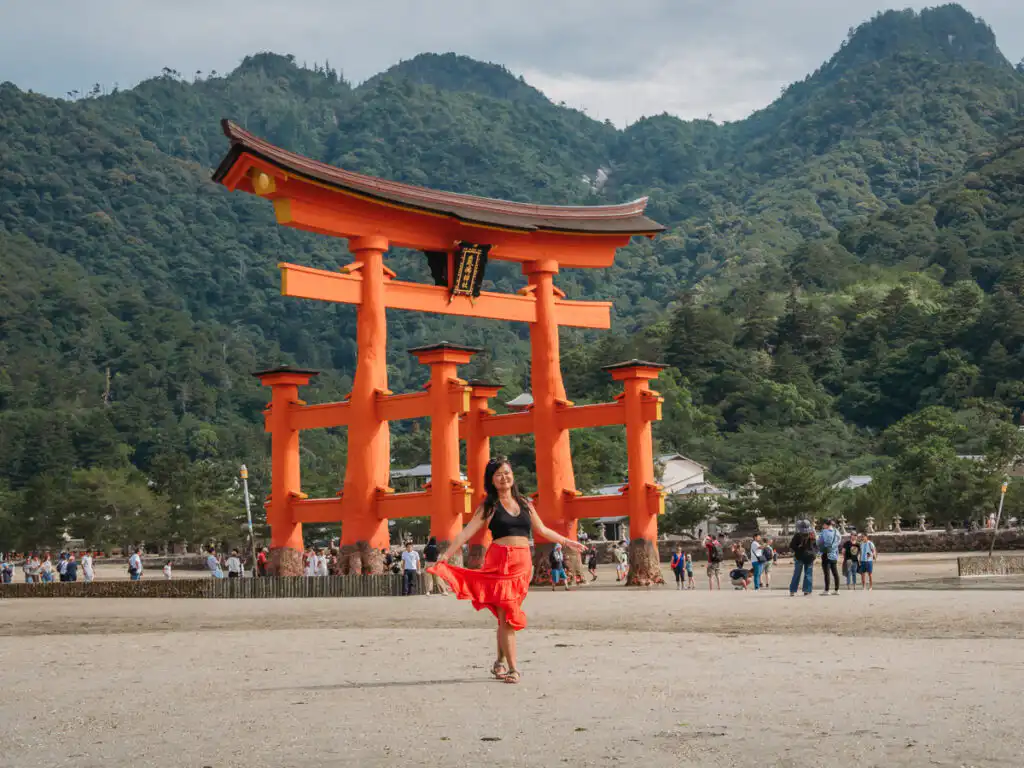 woman standing in front of the tori gate in Miyajima during low tide
