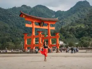 woman standing in front of the tori gate in Miyajima during low tide